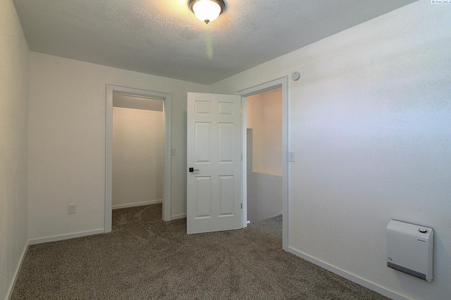 unfurnished bedroom featuring a textured ceiling, carpet, and baseboards