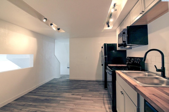 kitchen featuring tasteful backsplash, white cabinets, dark wood finished floors, black appliances, and a sink