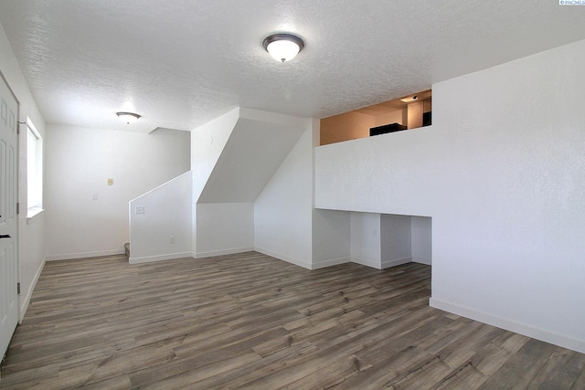 bonus room with a textured ceiling, baseboards, and wood finished floors