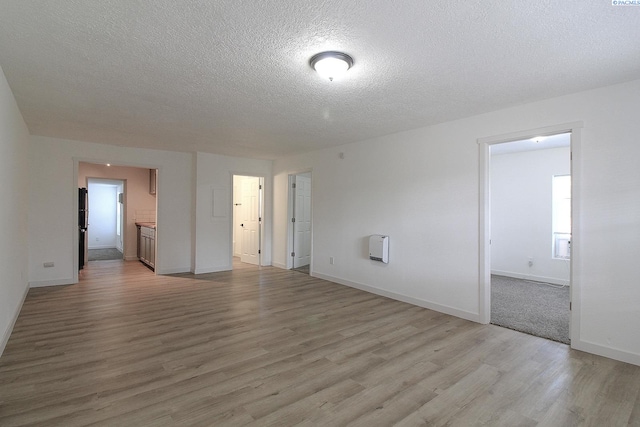 empty room with a textured ceiling, baseboards, and wood finished floors