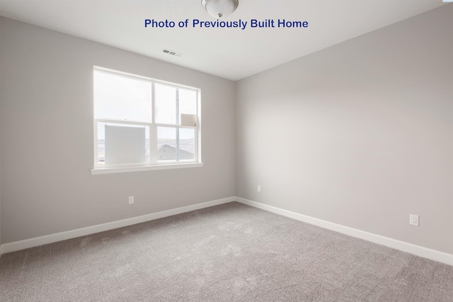 spare room featuring baseboards, visible vents, and carpet flooring