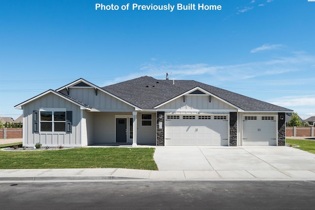 view of front of home featuring a garage, a front lawn, board and batten siding, and a shingled roof