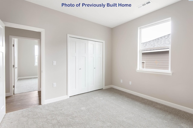 unfurnished bedroom featuring a closet, visible vents, light carpet, and baseboards