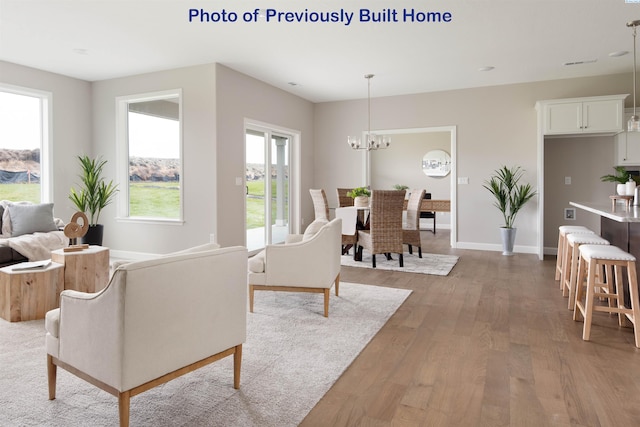 living area featuring a notable chandelier, baseboards, and wood finished floors