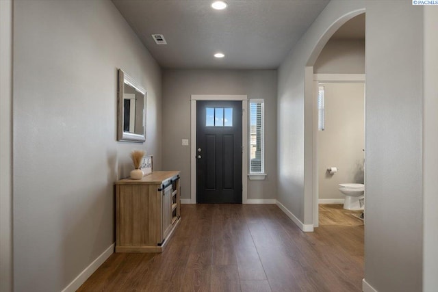 entrance foyer featuring arched walkways, recessed lighting, visible vents, baseboards, and dark wood finished floors