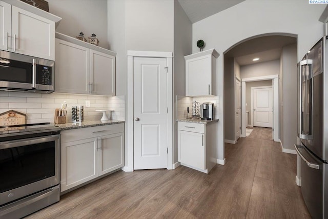 234 Ladera St, Prosser, WA 99350 - kitchen featuring light wood-style flooring, arched walkways, stainless steel appliances, and light stone counters