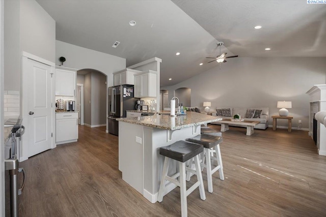 234 Ladera St, Prosser, WA 99350 - kitchen featuring arched walkways, high quality fridge, light stone counters, wood finished floors, and white cabinets