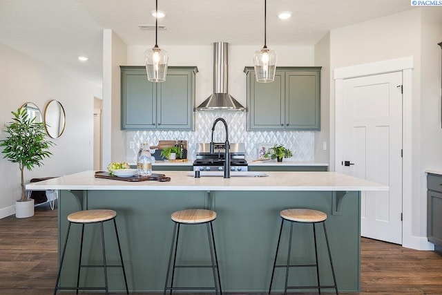 7080 W 34th Pl, Kennewick, WA 99338 - kitchen with wall chimney range hood, a kitchen bar, light countertops, dark wood finished floors, and recessed lighting