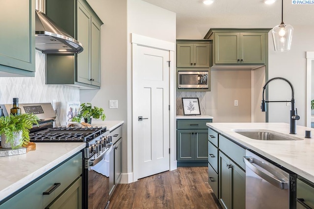 7080 W 34th Pl, Kennewick, WA 99338 - kitchen featuring appliances with stainless steel finishes, wall chimney range hood, a sink, green cabinets, and recessed lighting