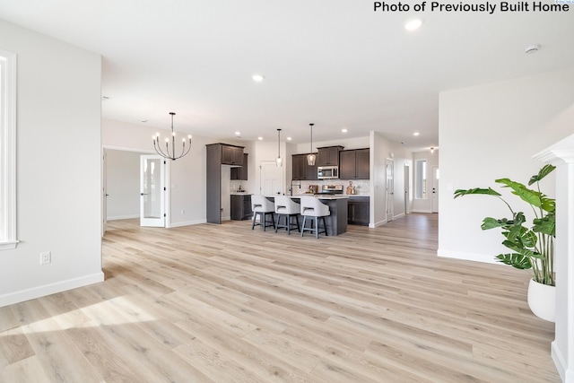 living area featuring baseboards, light wood finished floors, a chandelier, and recessed lighting