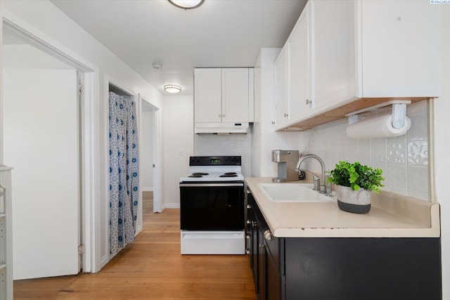 1205 N Union St, Kennewick, WA 99336 - kitchen with a sink, electric range oven, under cabinet range hood, white cabinets, and light wood-type flooring