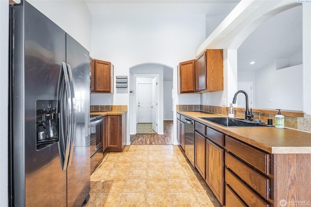 5905 W 4th Pl, Kennewick, WA 99336 - kitchen with brown cabinets, a sink, arched walkways, appliances with stainless steel finishes, and recessed lighting