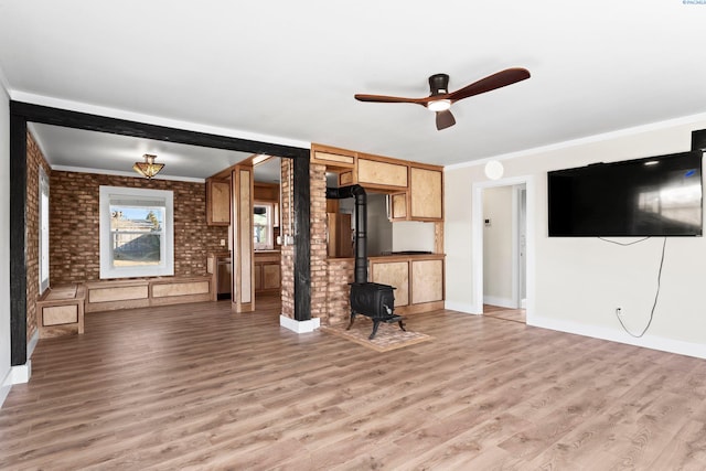 unfurnished living room featuring crown molding, brick wall, light hardwood / wood-style floors, and a wood stove