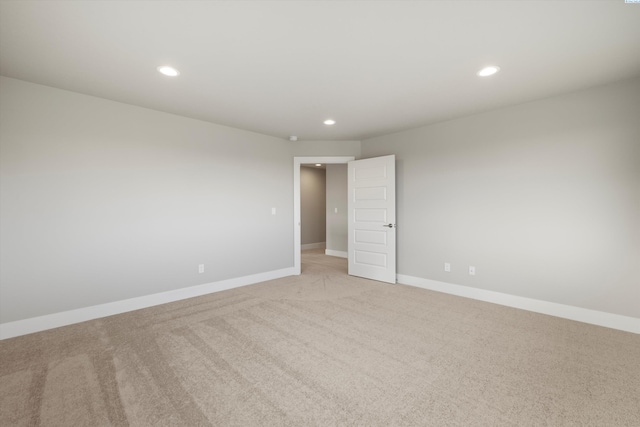 spare room featuring recessed lighting, light carpet, and baseboards