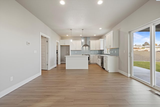 kitchen featuring a center island, decorative light fixtures, light countertops, white cabinets, and wall chimney exhaust hood