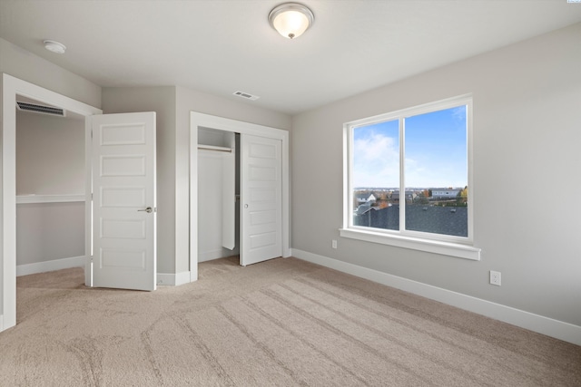 unfurnished bedroom featuring visible vents, baseboards, light colored carpet, a water view, and a closet