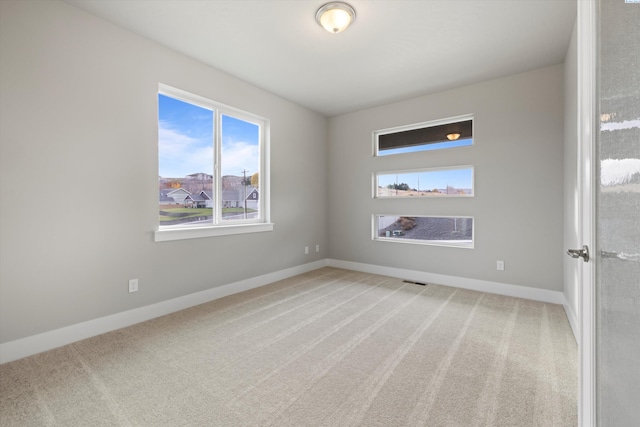 spare room with visible vents, baseboards, and carpet flooring