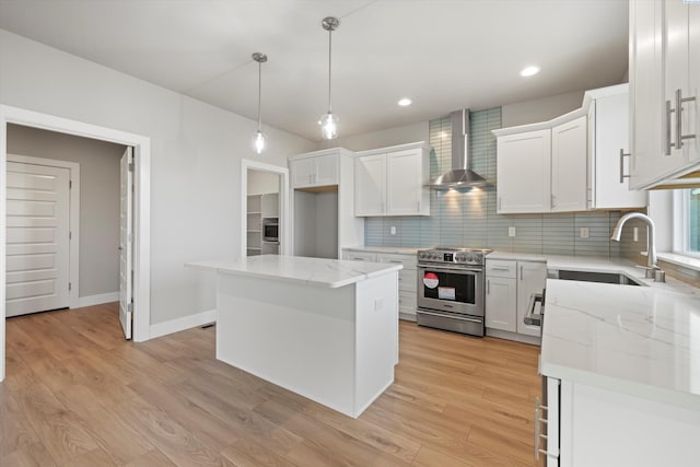 kitchen featuring appliances with stainless steel finishes, white cabinets, a kitchen island, and wall chimney exhaust hood