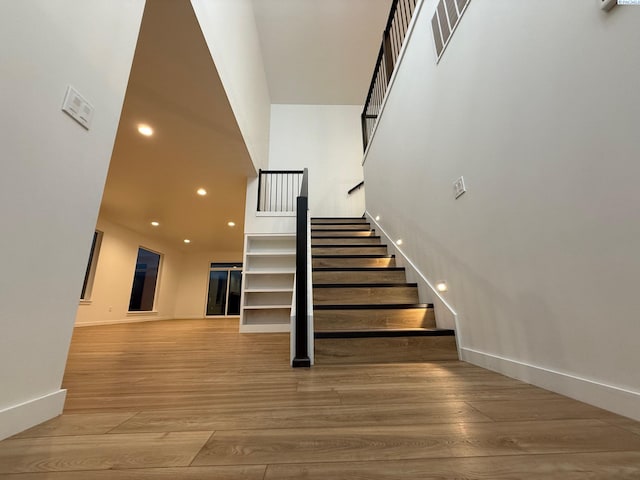 staircase featuring baseboards, visible vents, wood finished floors, and recessed lighting