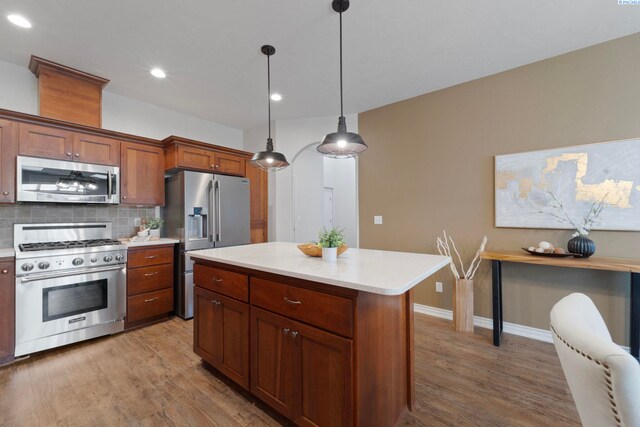 9411 Vincenzo Dr, Pasco, WA 99301 - kitchen featuring appliances with stainless steel finishes, wood finished floors, light countertops, tasteful backsplash, and pendant lighting