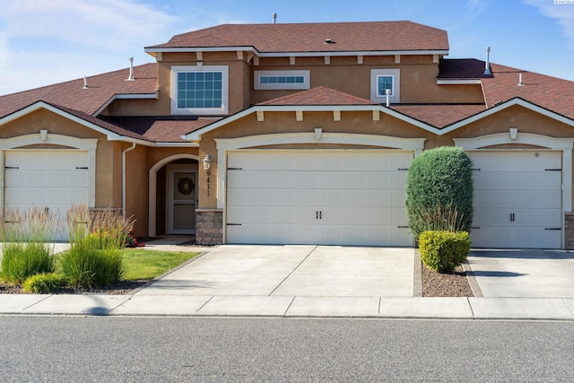 9411 Vincenzo Dr, Pasco, WA 99301 - view of front of property with stucco siding, a shingled roof, concrete driveway, and stone siding