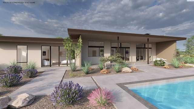 back of house featuring stucco siding and an outdoor pool