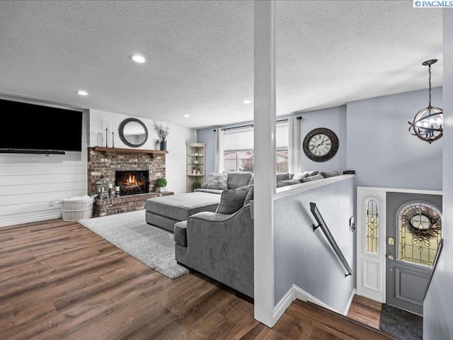 1842 Mahan Ave, Richland, WA 99354 - living room featuring wood finished floors, an inviting chandelier, recessed lighting, a textured ceiling, and a brick fireplace