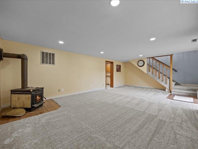 1842 Mahan Ave, Richland, WA 99354 - unfurnished living room with visible vents, carpet, a wood stove, and stairway