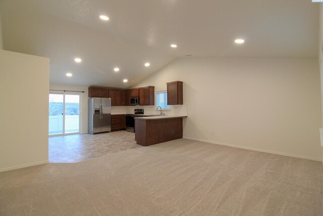 kitchen featuring appliances with stainless steel finishes, lofted ceiling, sink, kitchen peninsula, and light carpet