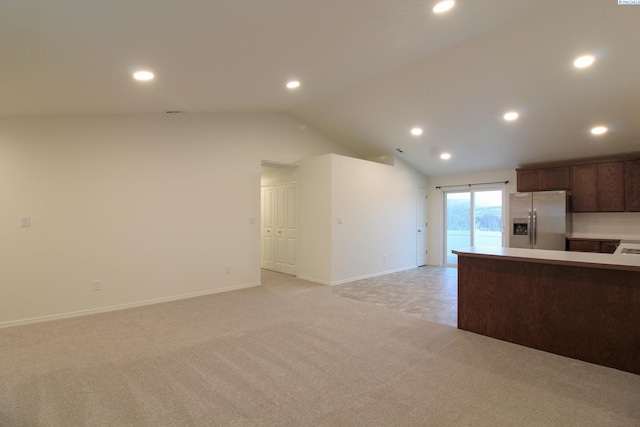 kitchen featuring stainless steel refrigerator with ice dispenser, vaulted ceiling, and light colored carpet