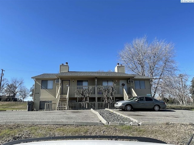 view of front of house with a chimney, a porch, and stairway