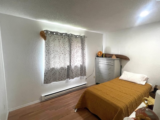 bedroom with baseboards, baseboard heating, and wood finished floors