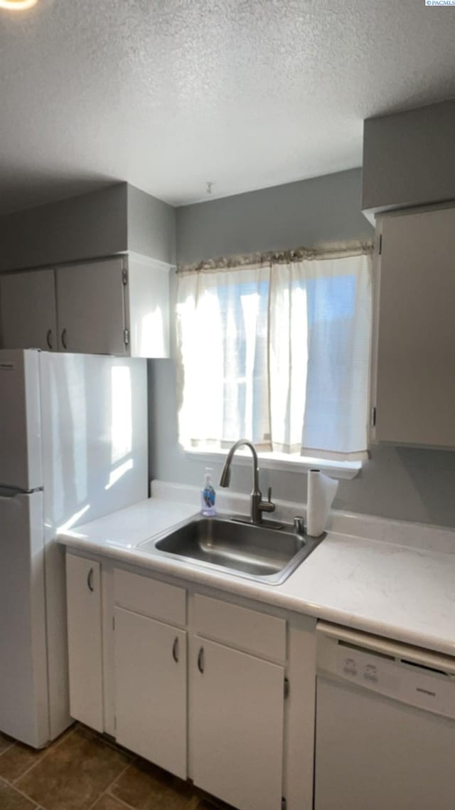 kitchen featuring a sink, white cabinetry, a textured ceiling, white appliances, and light countertops