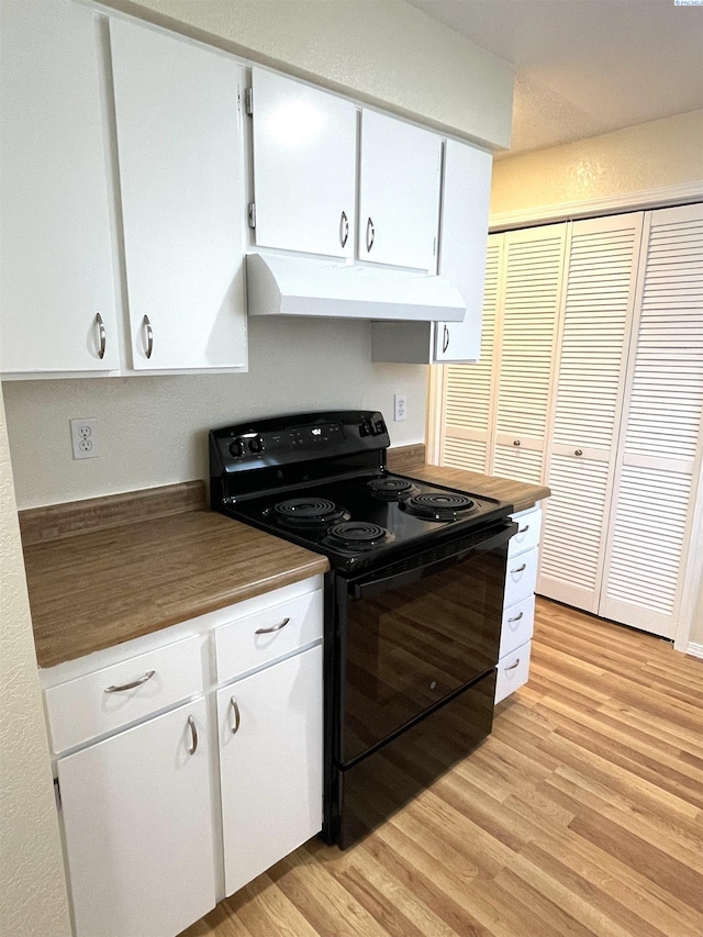 kitchen with black electric range oven, under cabinet range hood, light wood-style floors, white cabinetry, and dark countertops
