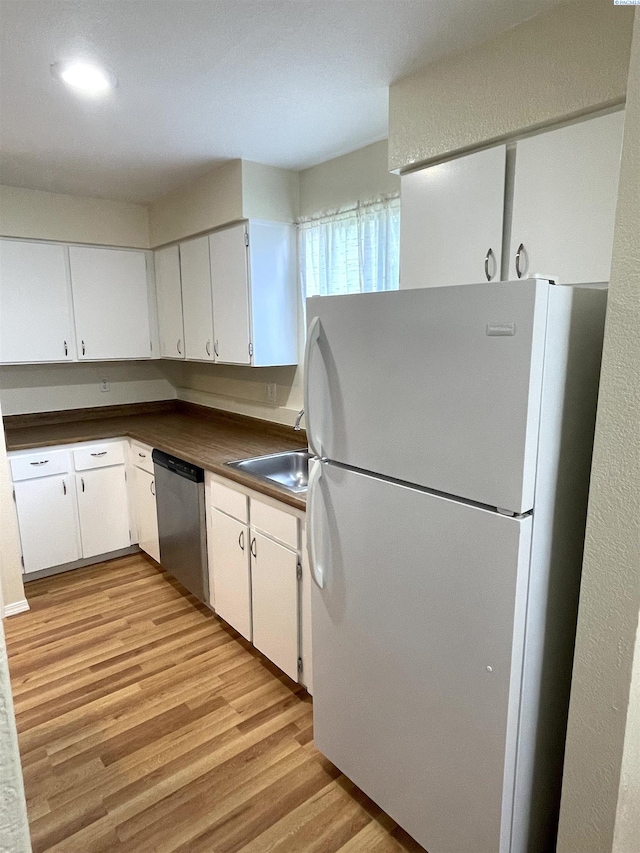 kitchen with freestanding refrigerator, light wood-type flooring, dishwasher, white cabinets, and dark countertops