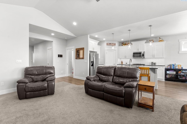 living area featuring lofted ceiling, light wood-style floors, recessed lighting, and baseboards
