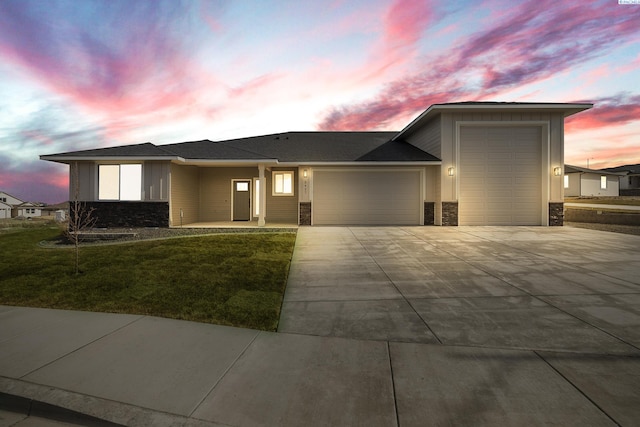 view of front of property with a garage, stone siding, driveway, and a front yard