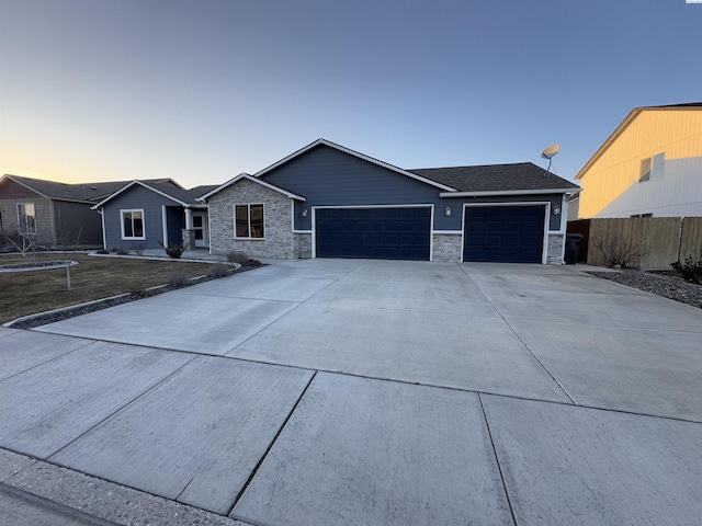 ranch-style home with an attached garage, fence, stone siding, and driveway