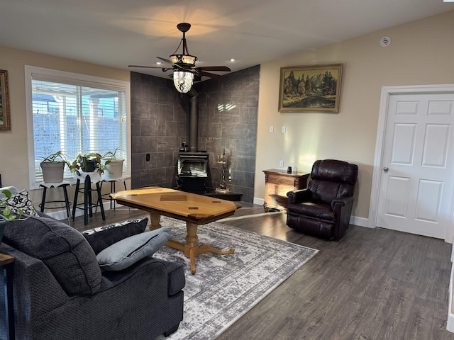 living area featuring lofted ceiling, a wood stove, baseboards, and dark wood-style flooring