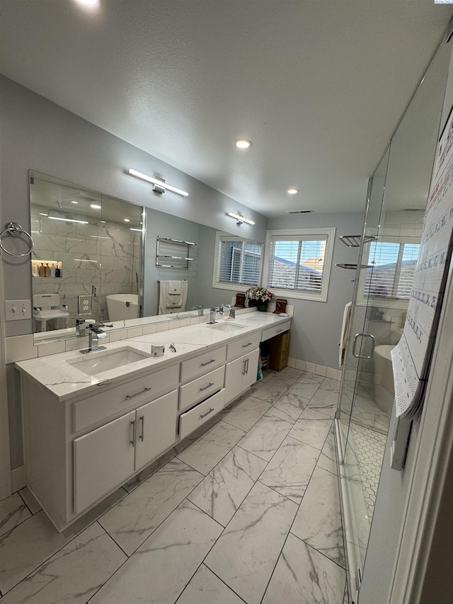 full bath with a sink, marble finish floor, a stall shower, and double vanity