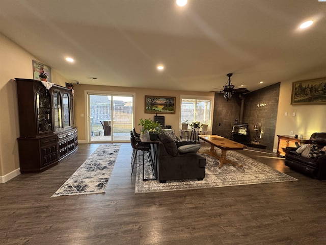 living room with recessed lighting, a wood stove, baseboards, and wood finished floors