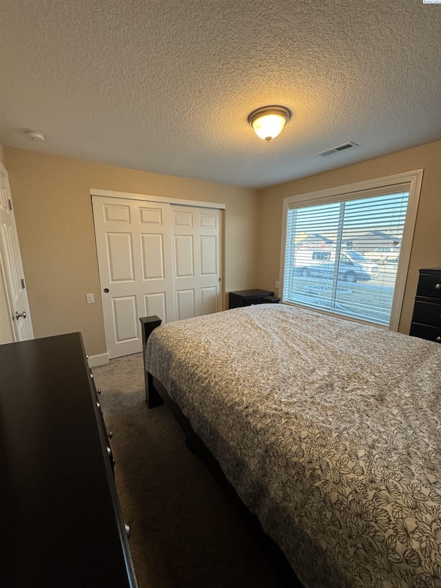 bedroom with a closet, a textured ceiling, visible vents, and carpet flooring