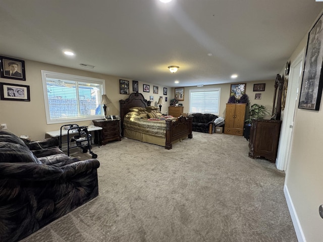 bedroom with visible vents, multiple windows, light colored carpet, and baseboards