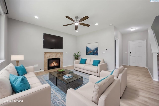 living area featuring light wood-style floors, a premium fireplace, ceiling fan, baseboards, and recessed lighting