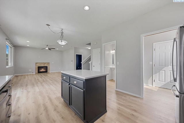 kitchen featuring a ceiling fan, freestanding refrigerator, light wood-style flooring, a glass covered fireplace, and recessed lighting
