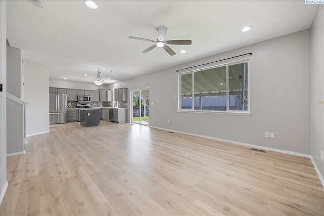 unfurnished living room featuring ceiling fan, baseboards, recessed lighting, and light wood-type flooring