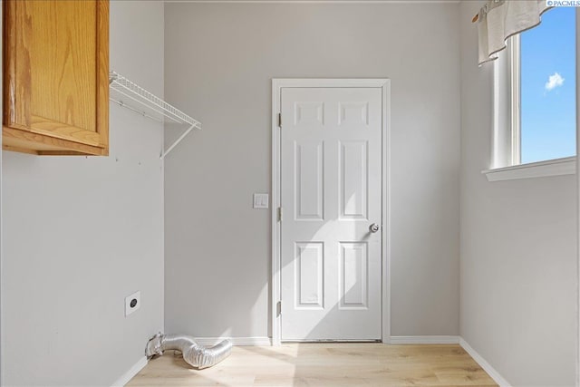 laundry room featuring cabinet space, wood finished floors, baseboards, and electric dryer hookup