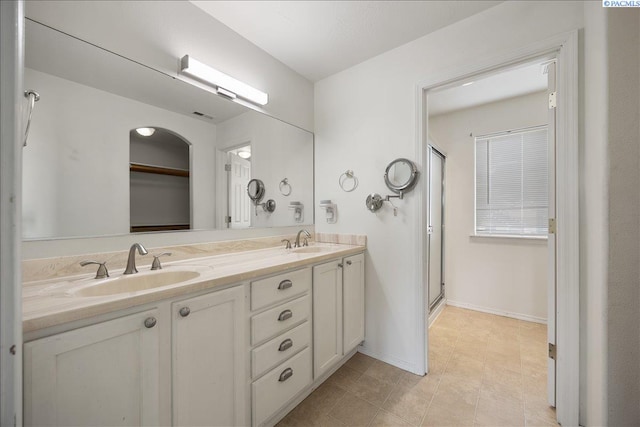bathroom featuring double vanity, a shower stall, and baseboards