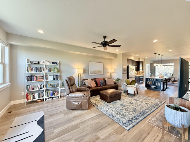 living room featuring light wood finished floors, baseboards, a ceiling fan, and recessed lighting