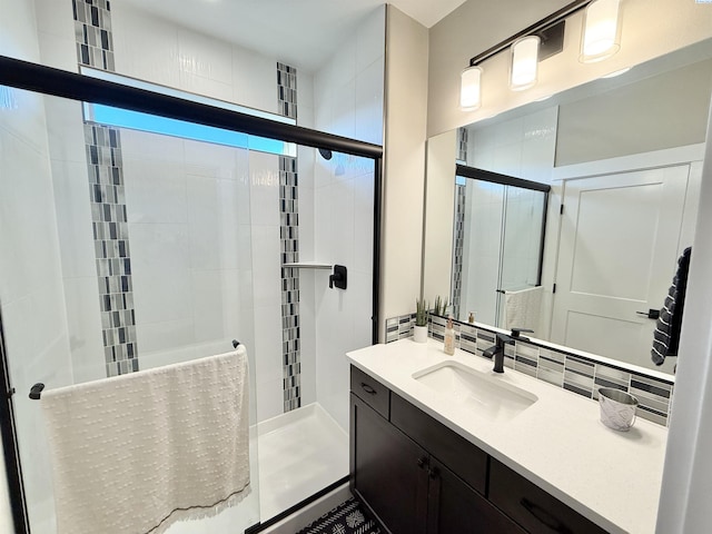 bathroom featuring tasteful backsplash, a tile shower, and vanity